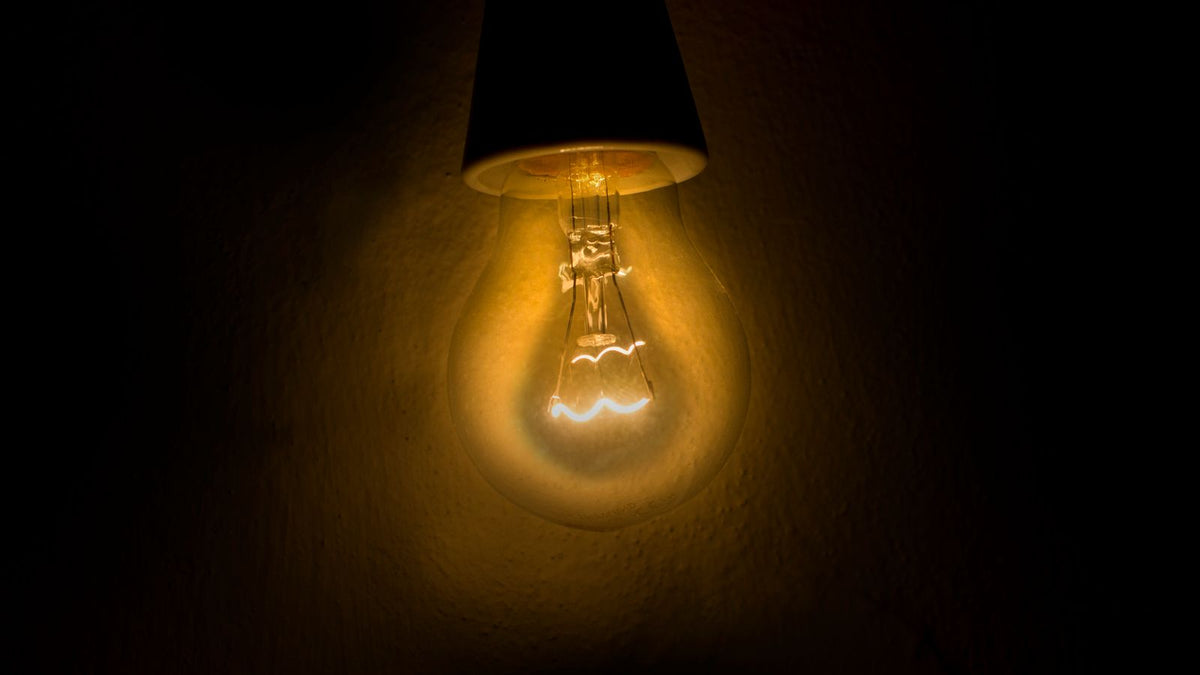 Ampoule allumée diffusant une lueur chaude sur fond sombre