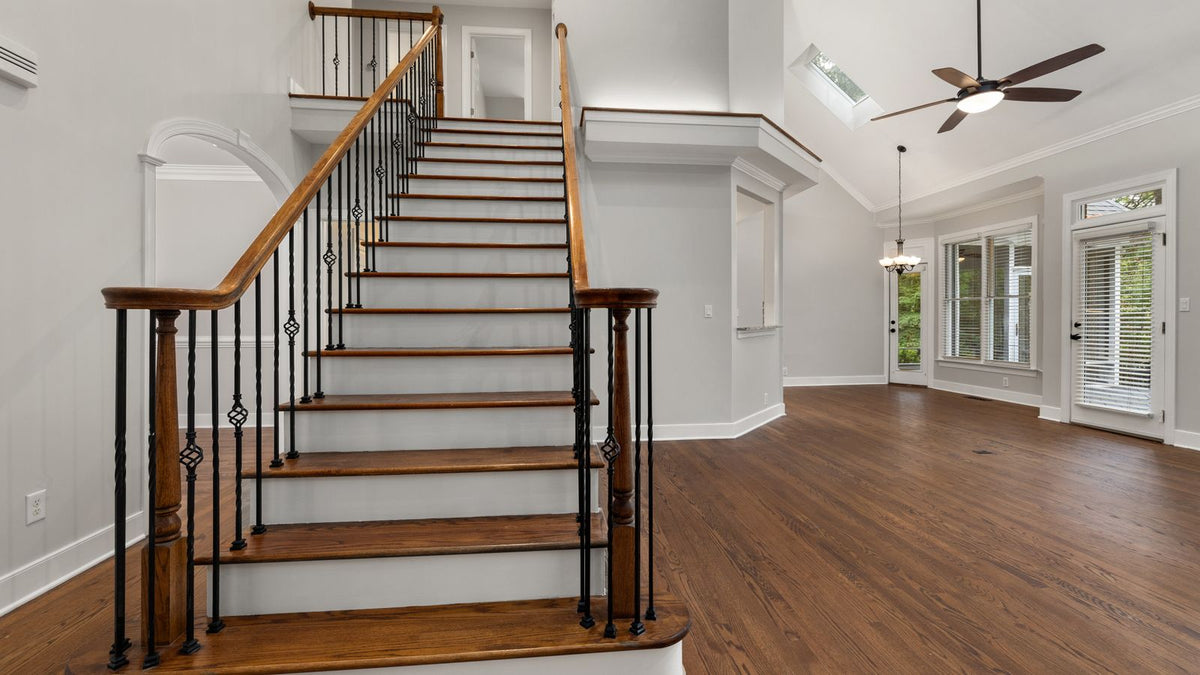 Salon à haut plafond avec escalier en bois, grand volume lumineux