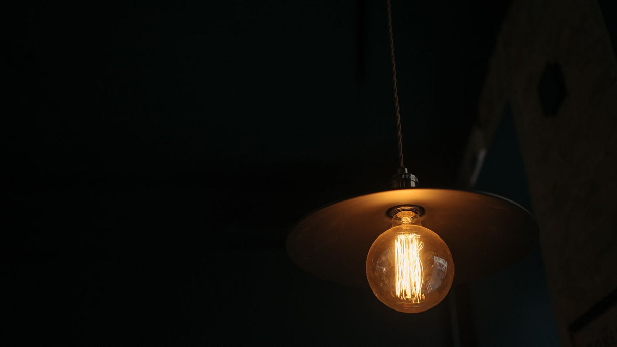 Ampoule suspendue à un câble textile diffusant une lueur chaleureuse