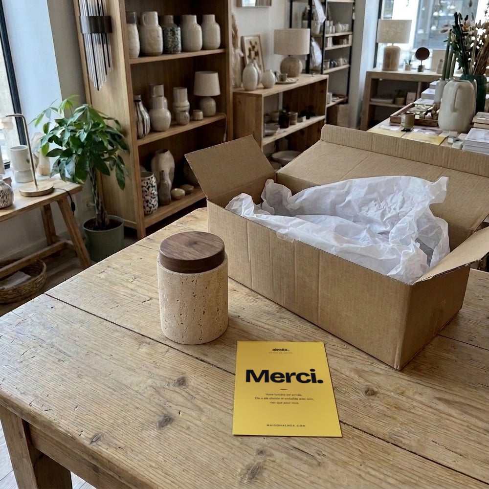 Plafonnier spot en travertin et noyer, déballé sur la table de la boutique avec la carte Merci #noyer