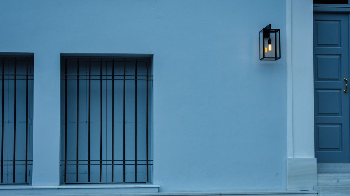 Applique extérieure noire fixée sur une façade bleue près d'une fenêtre