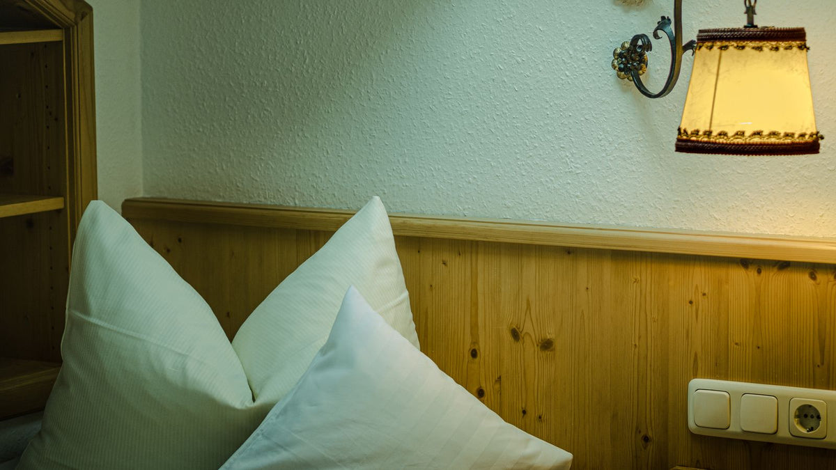 Chambre chaleureuse aux murs en bois avec applique murale au-dessus du lit