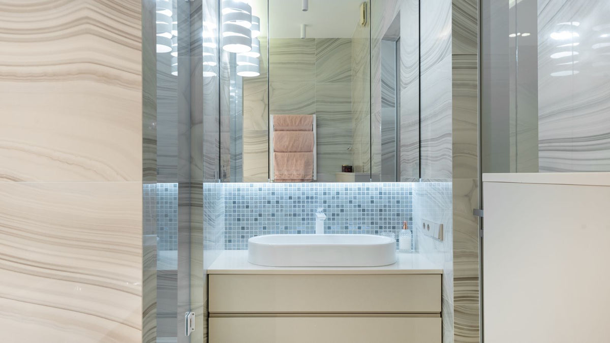 Petite salle d'eau au carrelage beige avec miroir éclairé et lavabo