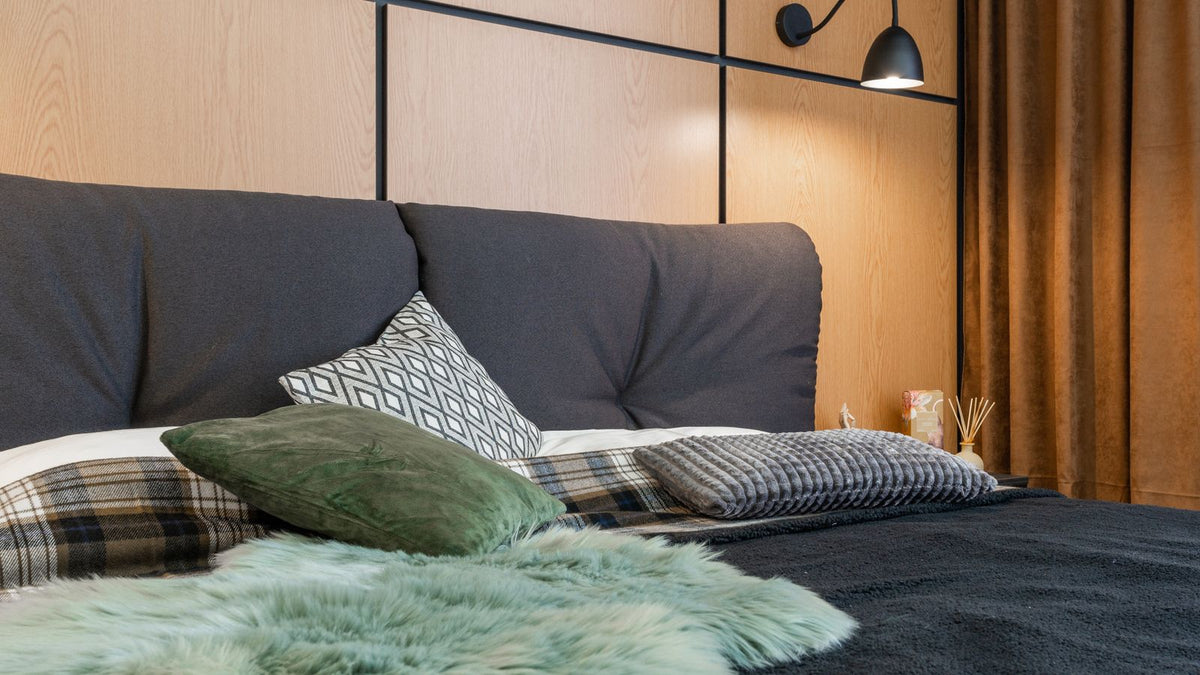 Lit cosy avec applique murale à bras noir au-dessus de la tête de lit