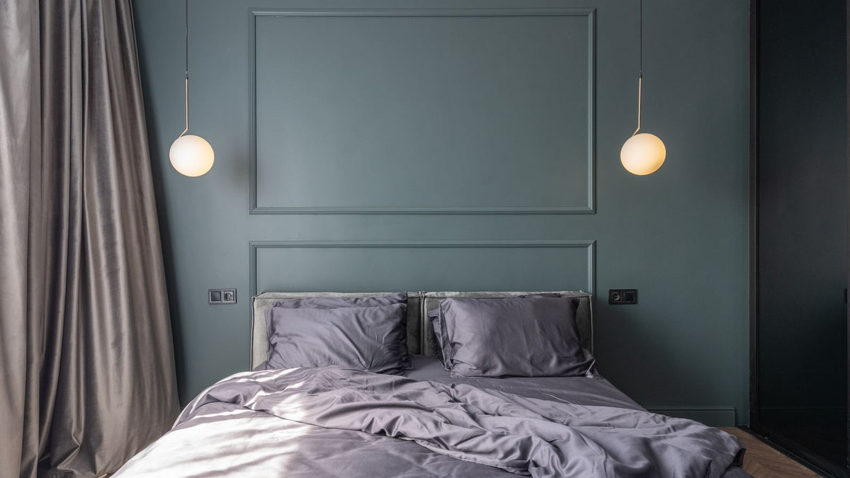 Chambre au mur vert sombre avec deux appliques symétriques au-dessus du lit