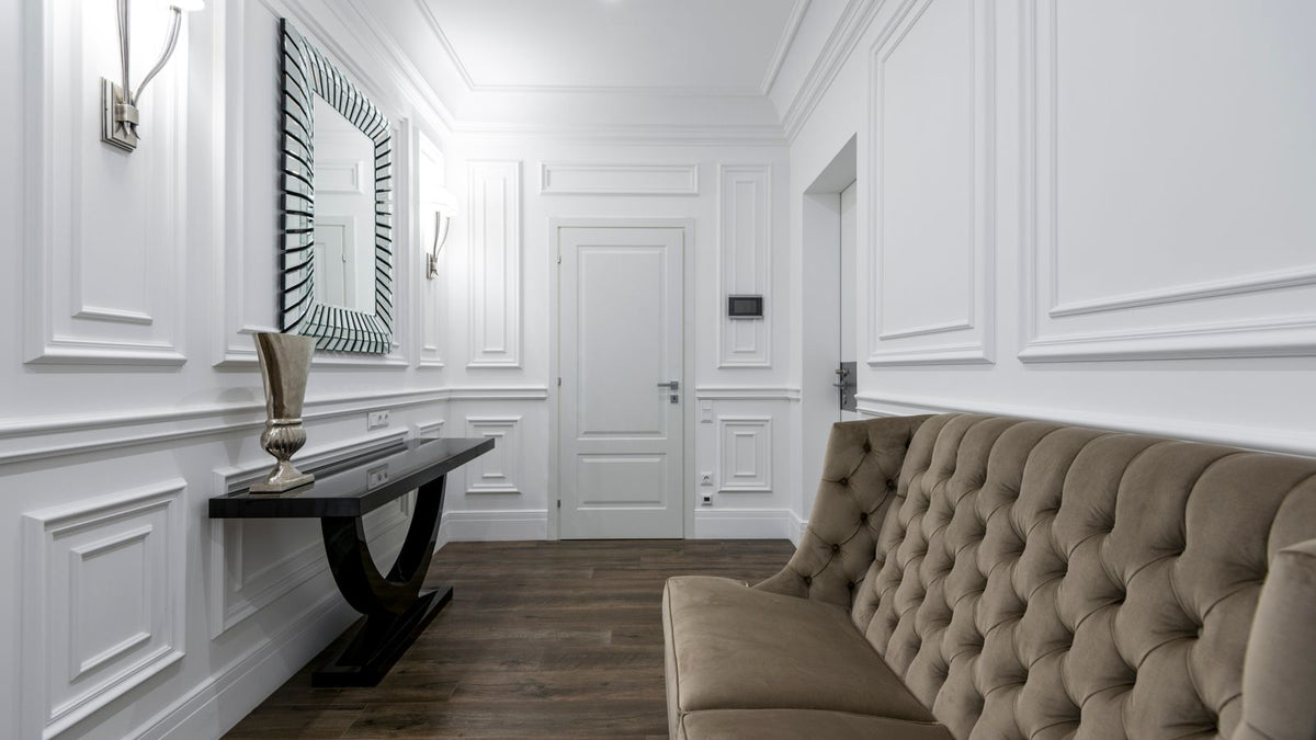 Entrée aux murs moulurés blancs avec banquette et lumière douce