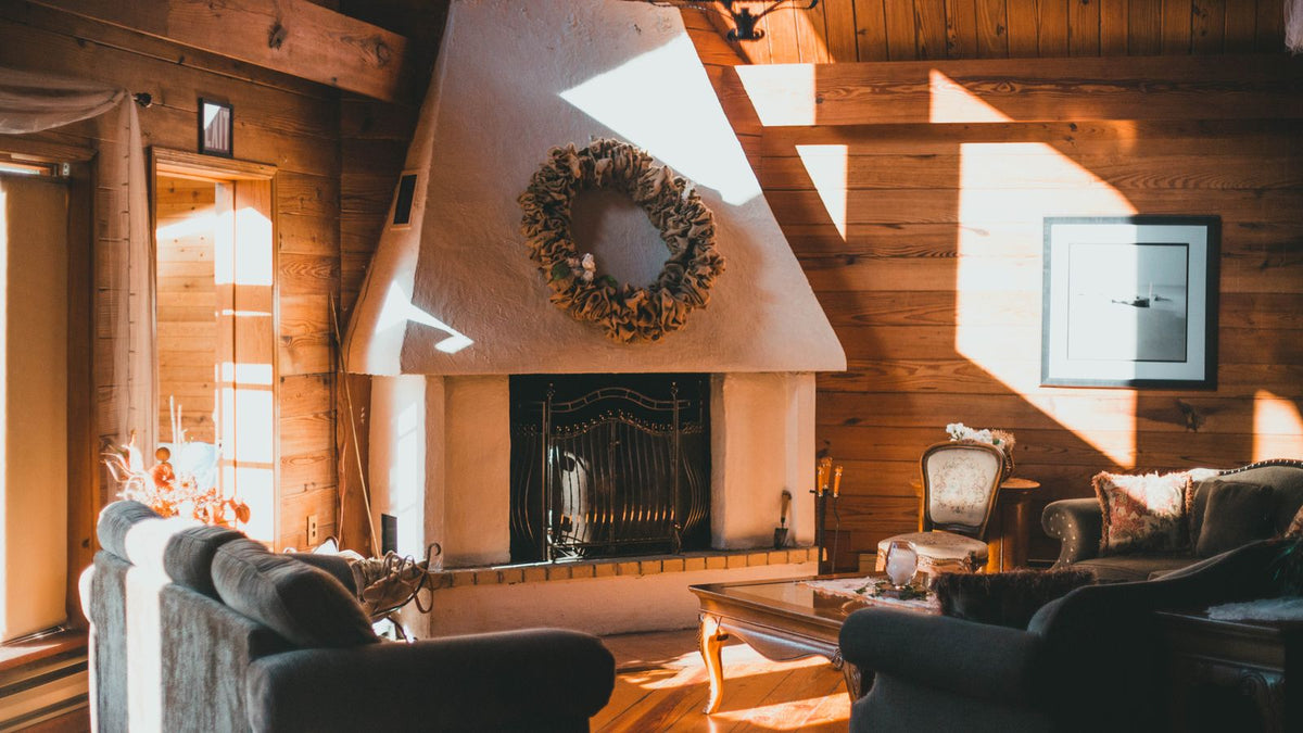 Salon cocooning en bois avec cheminée allumée et couronne d'hiver