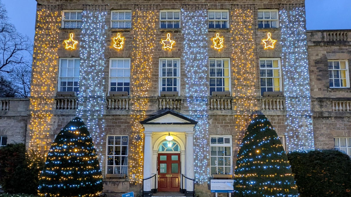 Façade de maison illuminée pour Noël avec sapins décorés