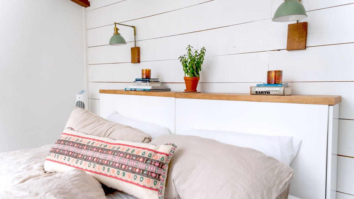 Chambre blanche avec deux lampes murales à brancher au-dessus du lit