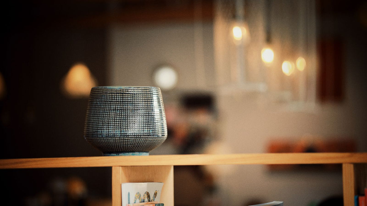 Intérieur chaleureux où une lampe sans fil éclaire un vase texturé
