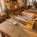 Applique vague blanche de 60 cm posée sur une table de boutique, à côté de son carton et de la carte Merci #blanc